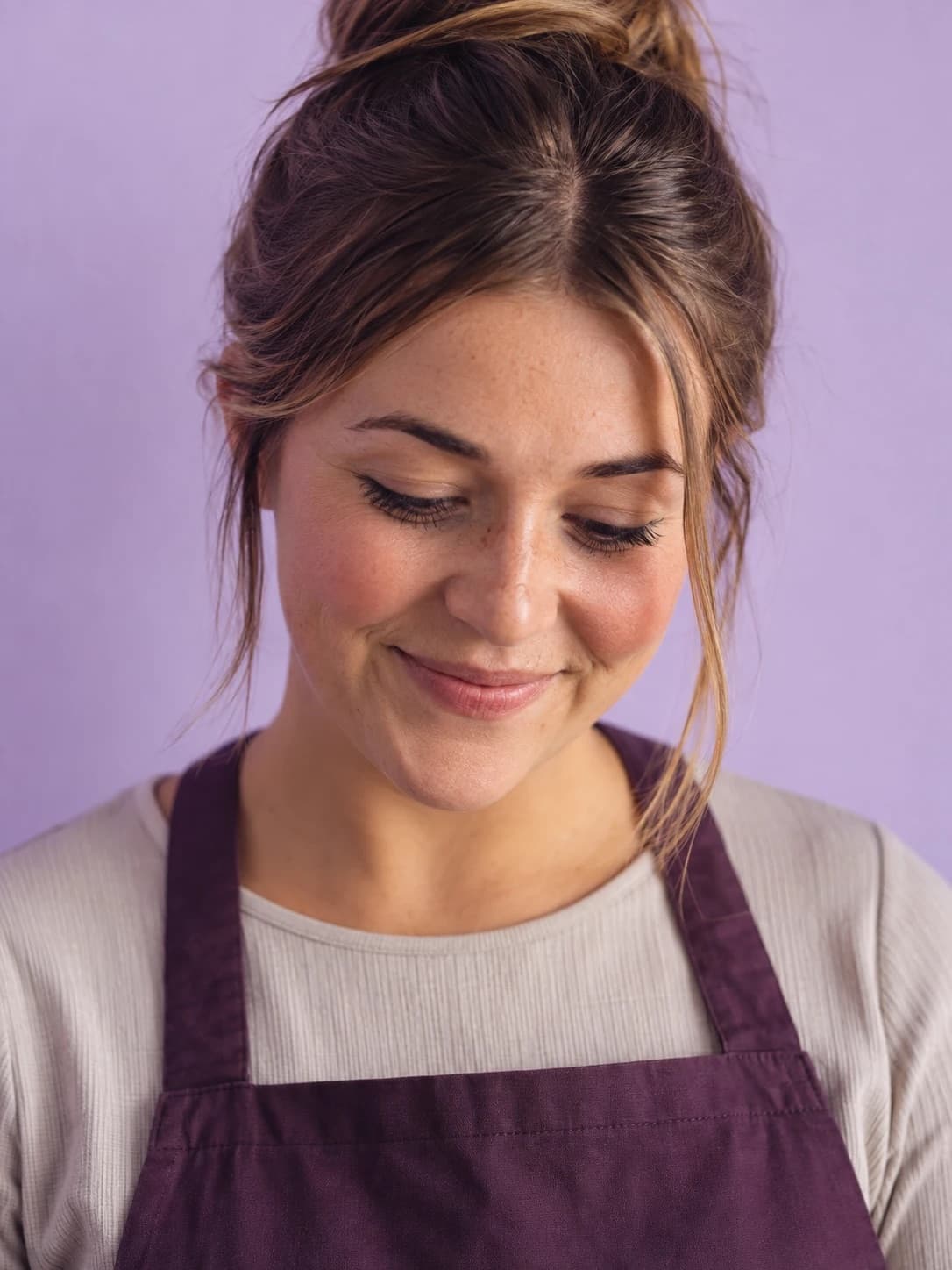 An educator in a plum apron smiling down at a message